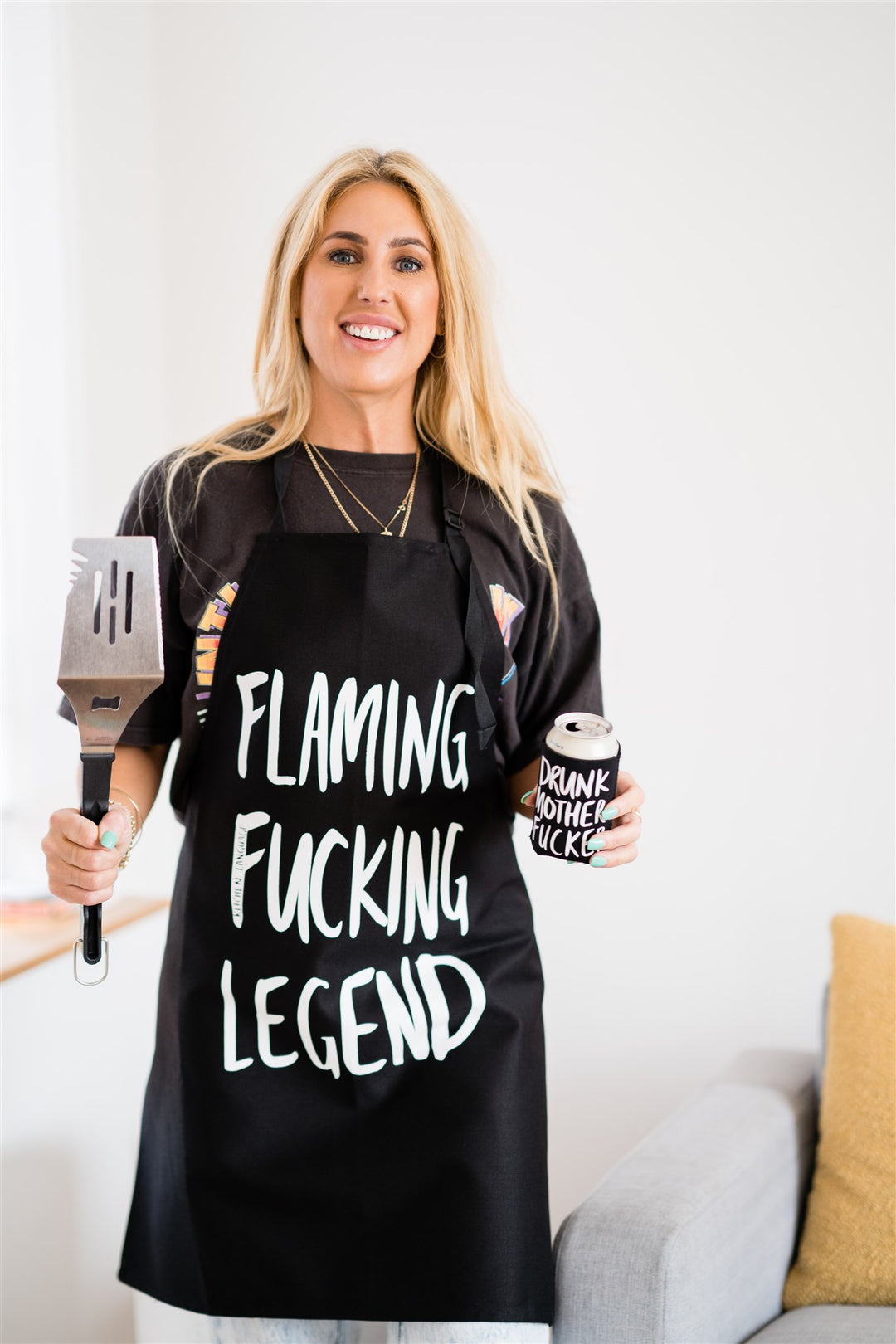 Chick wearing a Flaming Fucking Legend apron with Drunk Mother Fucker stubby holder